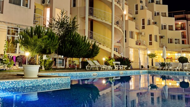 Ein mehrstöckiges Hotel mit Schwimmbad, Außenbereich und gut beleuchteter Fassade.