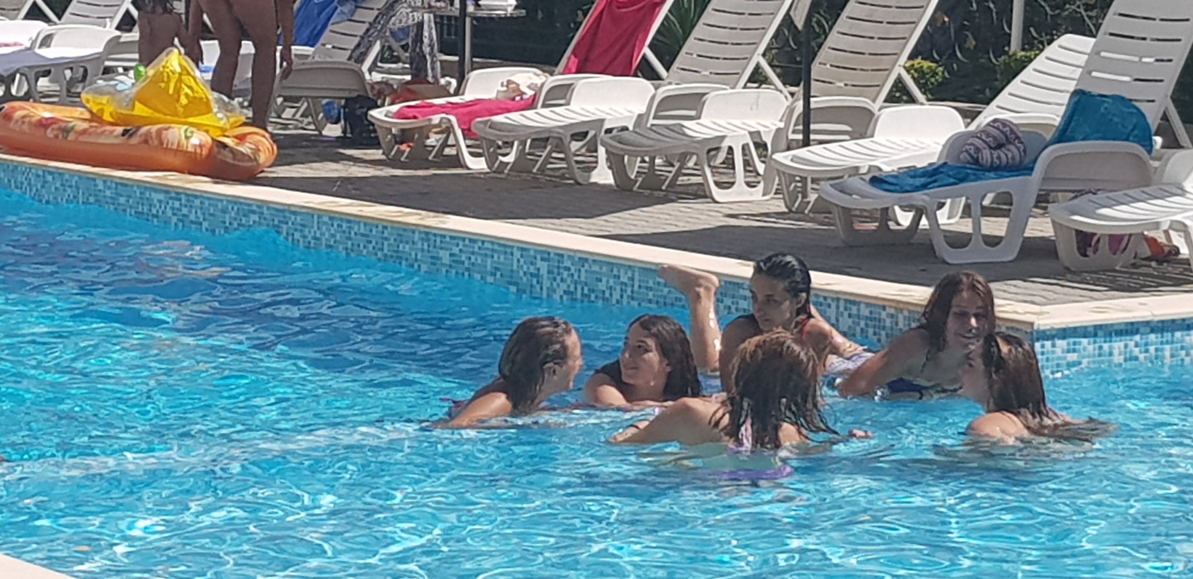 A swimming pool with lounge chairs and a lifeguard stand.