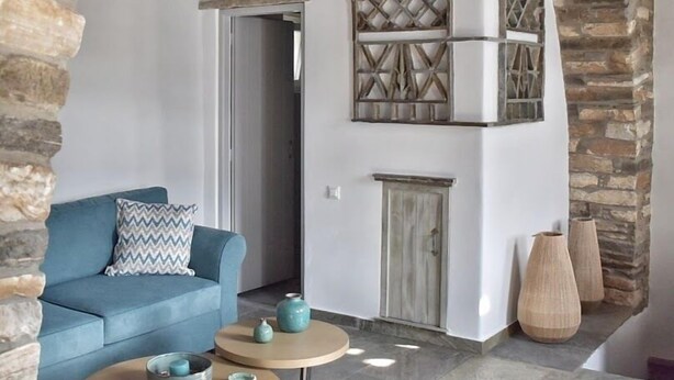 A cozy living room with a blue sofa, a small round table, and decorative vases. - Tinoshomelidays Residences (Tinos)