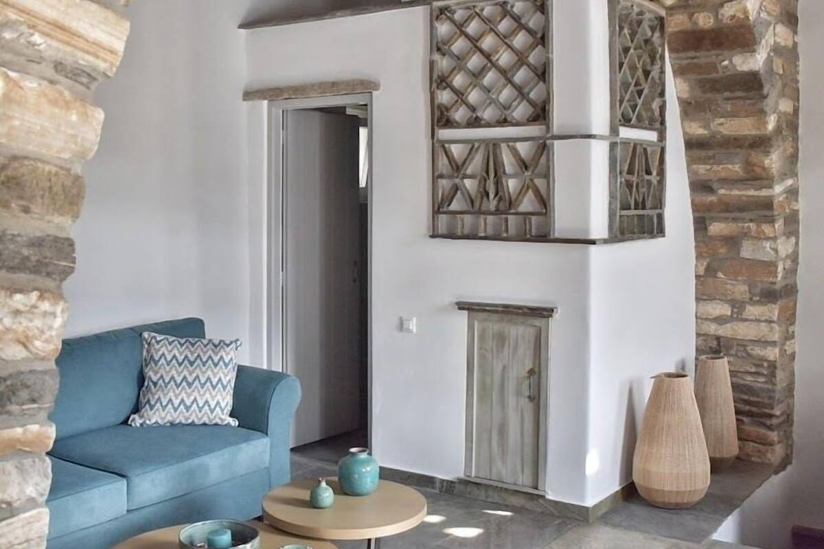 Een gezellige woonkamer met een blauwe bank, een klein rond tafeltje en decoratieve vazen.