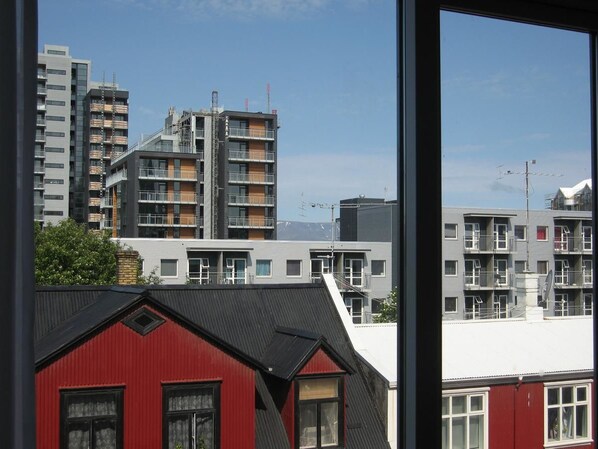 A view of modern buildings with balconies and a red building in the foreground.