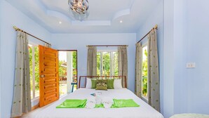 A bedroom with a large bed, wooden headboard, and curtains. - Rat Villa (Pa Klok)