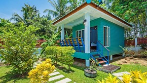 A small, single-story house with a porch, surrounded by lush greenery and a clear sky. - Rat Villa (Pa Klok)