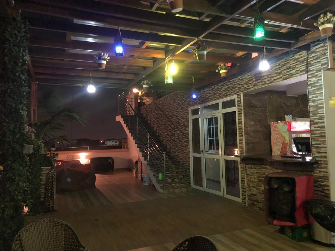 Un amplio espacio exterior con terraza de madera, pared de piedra y escalera que conduce a un nivel superior.