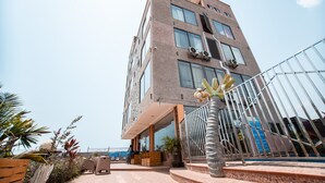 Un hôtel à plusieurs étages au design moderne, doté d’un balcon avec des meubles d’extérieur et des plantes en pot.