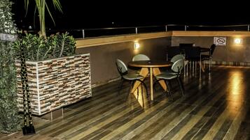 Una terraza en la azotea con una mesa redonda y sillas, rodeada por un muro bajo con un diseño decorativo.