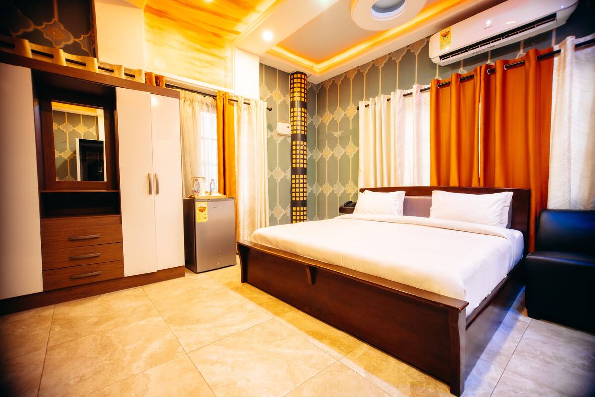 Habitación de hotel con cama, armario, escritorio y aire acondicionado.