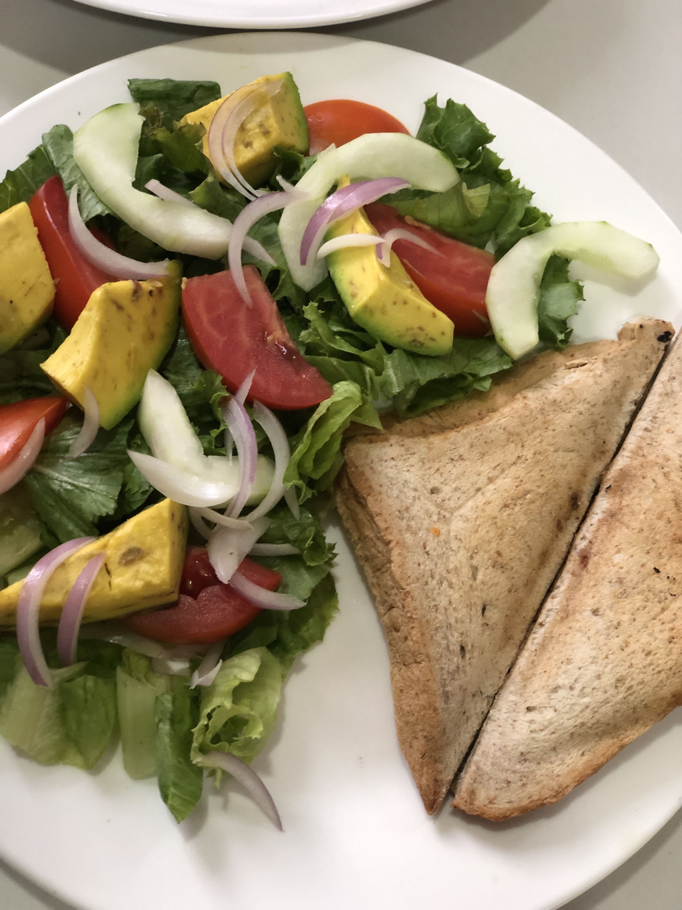 Une assiette avec une salade et deux tranches de pain grillé.