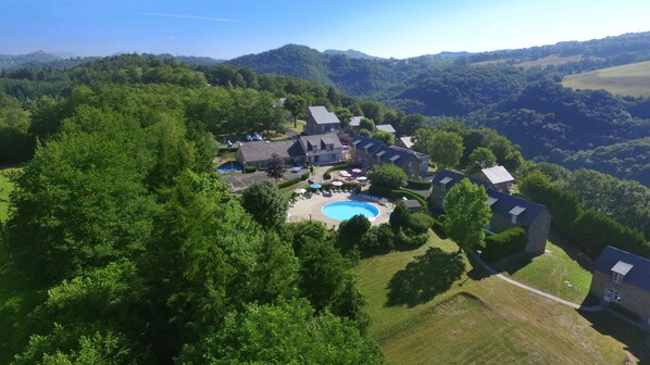 Vista aérea de una zona residencial con piscina rodeada de casas y abundante vegetación.
