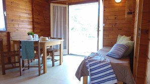 Une cabane en bois avec un lit, une table et des chaises.