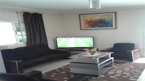 Un salon avec un canapé, une table basse, un téléviseur et un tableau accroché au mur.