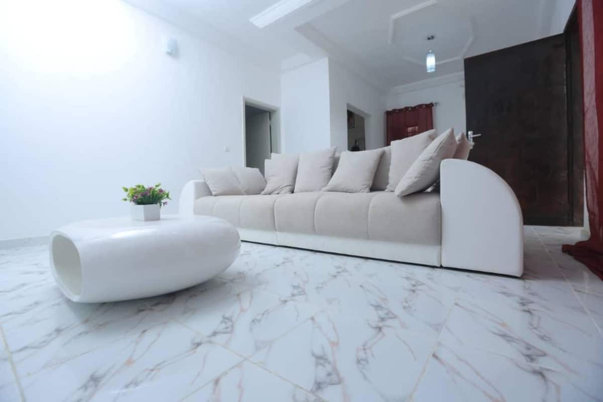 A modern living room with a white sofa, a white coffee table, and a marble floor.
