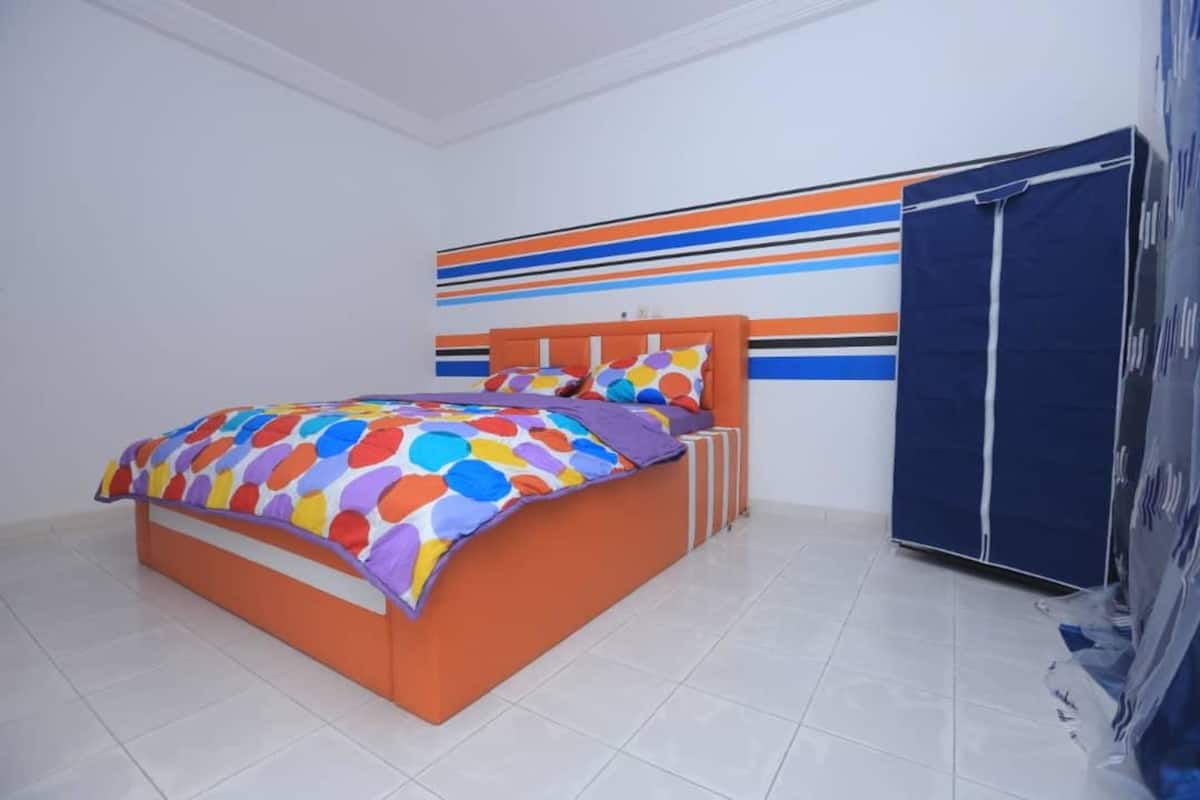 A bedroom with a bed, a wardrobe, and a wall with horizontal stripes.