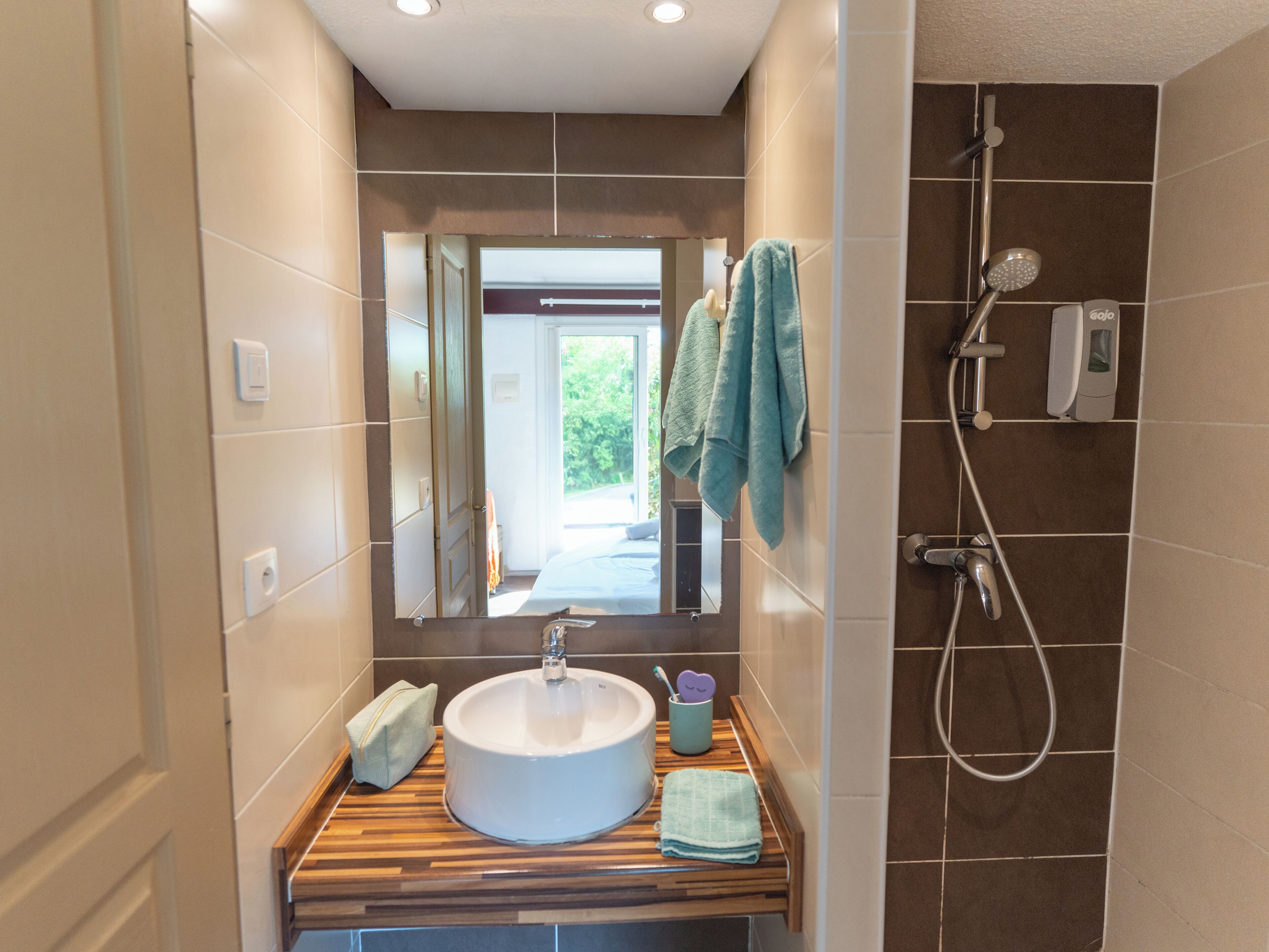 A bathroom with a sink, mirror, and shower.