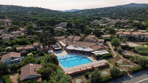 An aerial view of a residential area with a large swimming pool surrounded by houses and greenery.