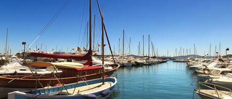 A marina with various boats docked, clear skies, and calm water.