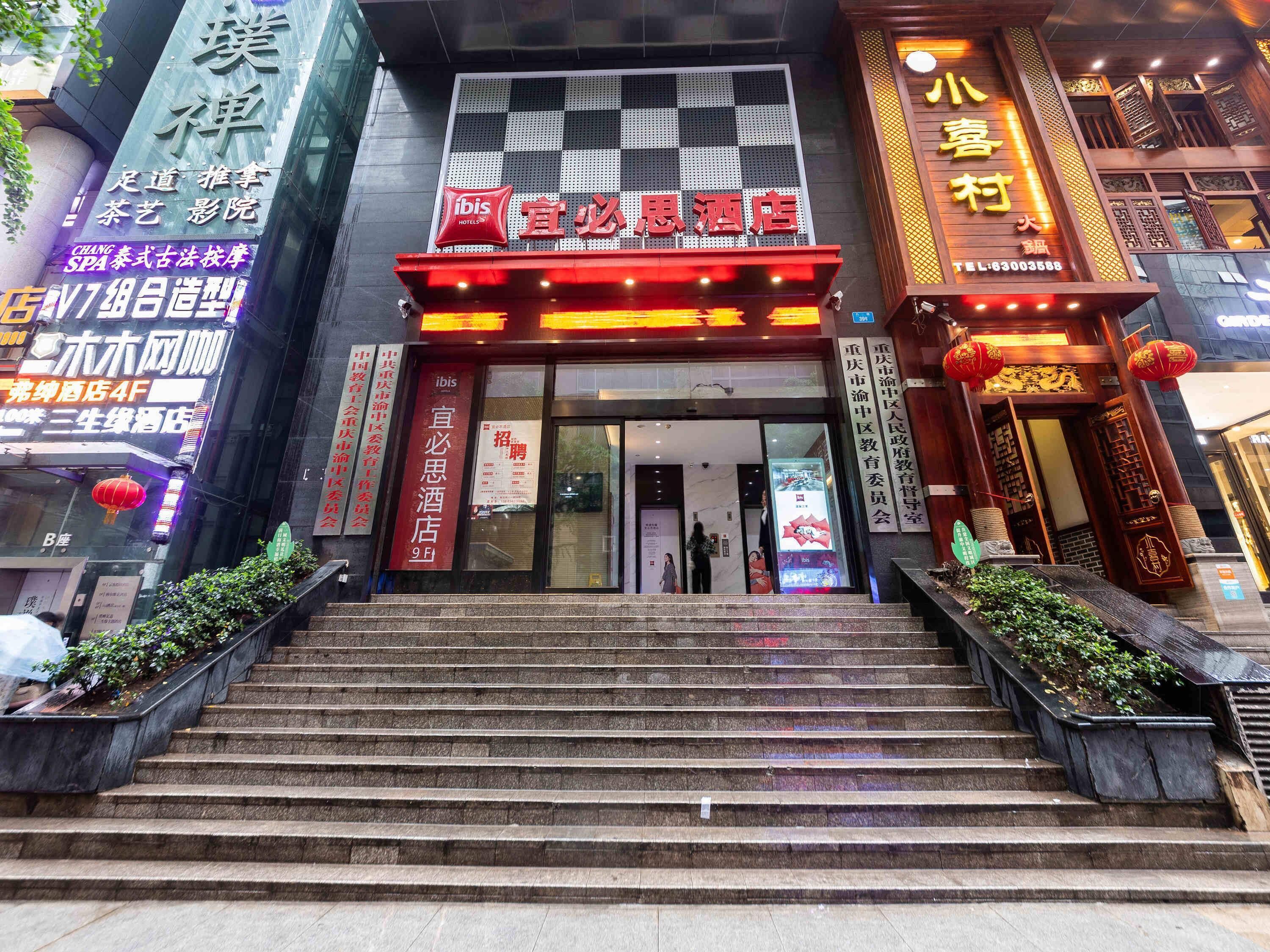 A hotel entrance with a red sign, steps leading up to it, and various other signs and decorations around.