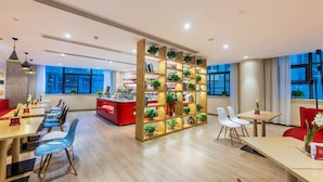 A modern hotel lobby with a reception desk, seating area, and a plant-filled partition. - Ibis Chongqing Jiefangbei Pedestrian Street Hotel (Chongqing)