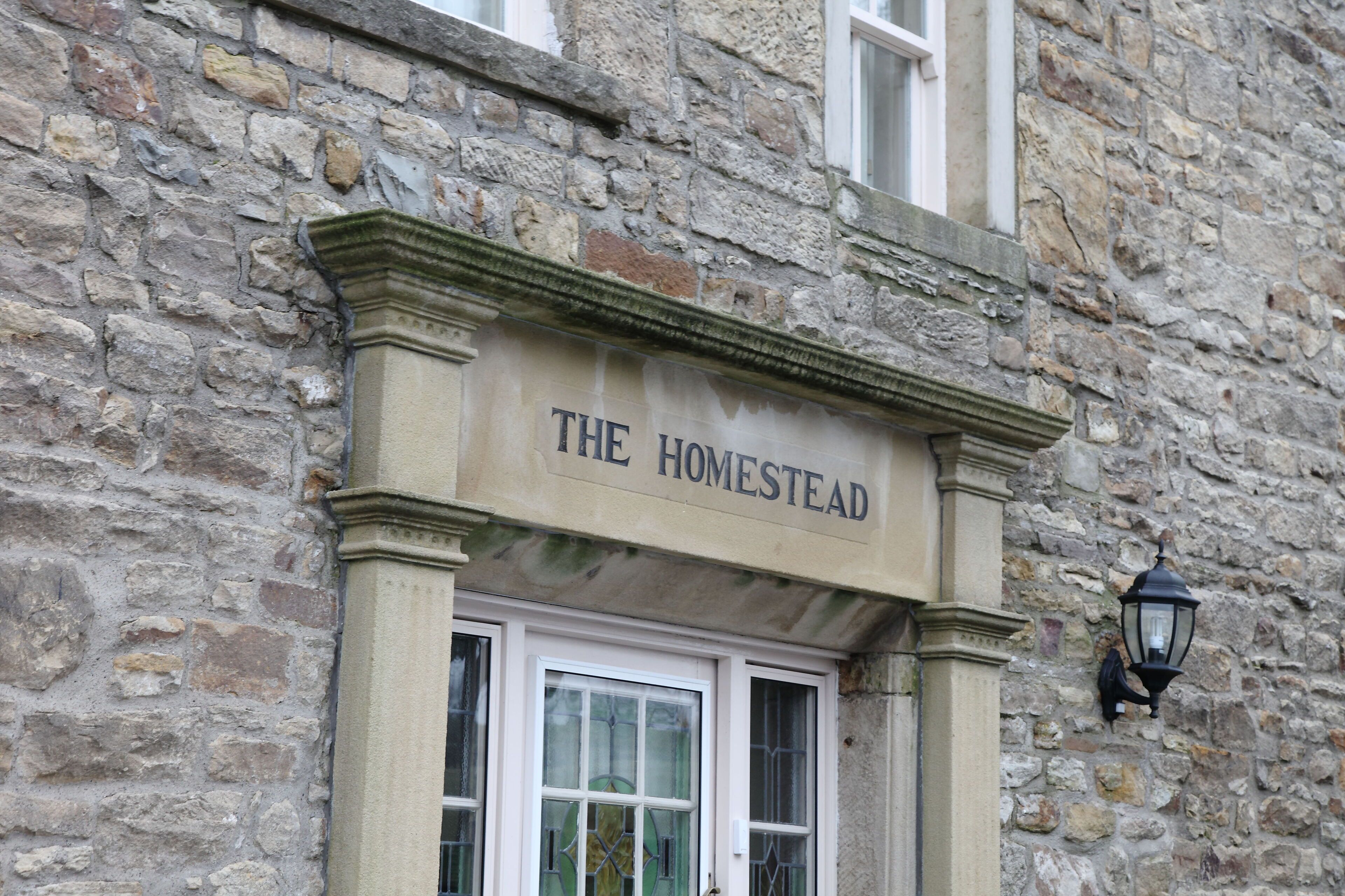 Un edificio in pietra con un'insegna che recita 'THE HOMESTEAD'.