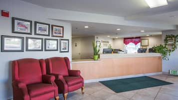 A reception area with a reception desk, framed pictures on the wall, and a red sofa.