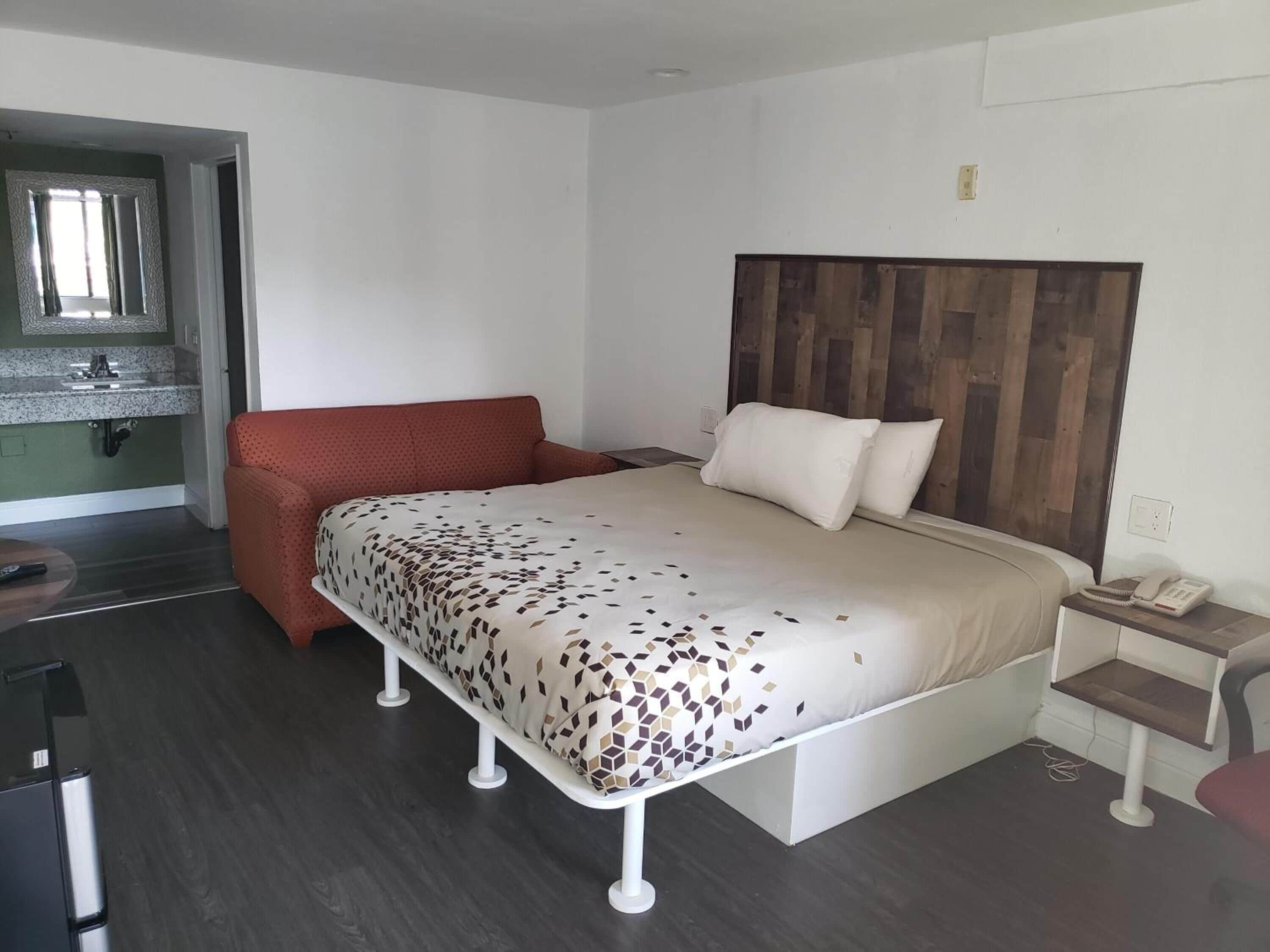 Una camera da letto moderna con un letto, una piccola scrivania e un divano rosso.