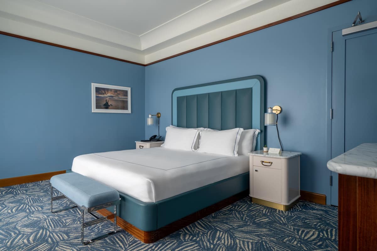 A neatly arranged bedroom with a large bed, bedside tables, and a bench.