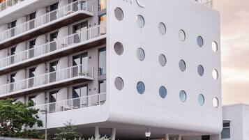 Un edificio moderno con un llamativo letrero 'Mr C', varios balcones y un diseño de ventanas circulares distintivo.