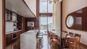 A modern kitchen with a central island, bar stools, and a dining area with a glass table and chairs.