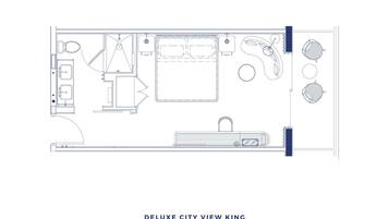 A floor plan of a hotel room labeled "Deluxe City View King," featuring a large bed, a separate bathroom, a small seating area, and a view of the city.