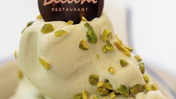 Un postre con una porción de chocolate que lleva la etiqueta "Bellini Restaurant", decorado con pistachos picados.