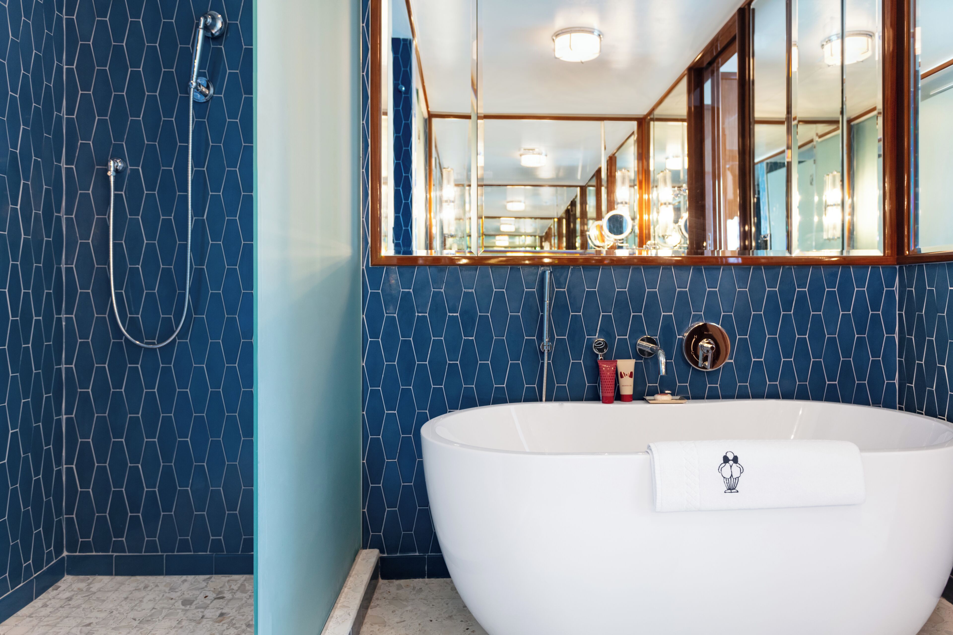 Un baño moderno con una bañera independiente, ducha y un espejo grande.