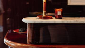 Un coin bar doté d’un comptoir en marbre, d’une lampe en laiton et d’une bougie.