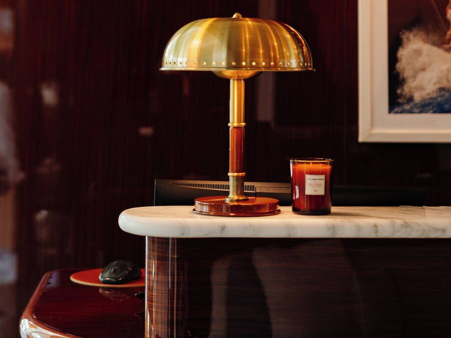 Un coin bar doté d’un comptoir en marbre, d’une lampe en laiton et d’une bougie.