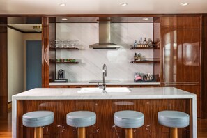 A modern kitchen with a large island, bar stools, and built-in shelves.
