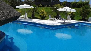 A swimming pool with lounge chairs and umbrellas. - Palmera Beach Hotel (Chihuahua)