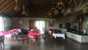 A restaurant with multiple tables and chairs, a tiled floor, and hanging light fixtures. - Palmera Beach Hotel (Chihuahua)