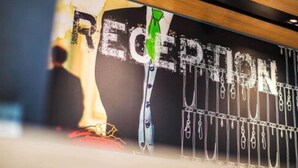 Un área de recepción con un letrero que dice "RECEPTION" y una persona parada frente a él.