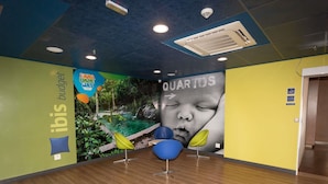 Una habitación con piso de madera, un mural con la imagen de un bebé y un cartel que dice 'ibis budget'.
