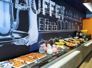A breakfast buffet with various food items and a large mural in the background. - ibis budget Parauapebas (Parauapebas)