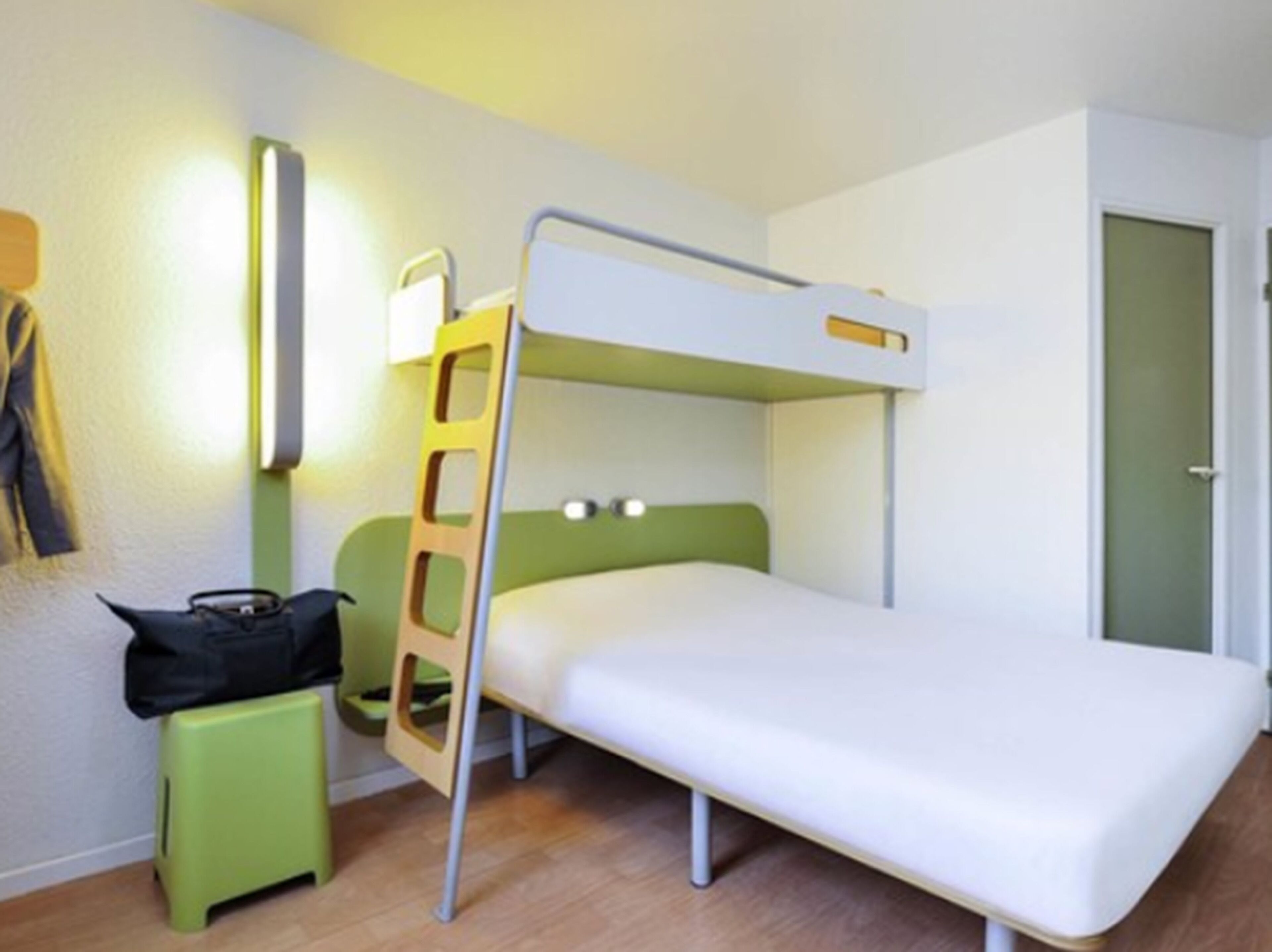 A bunk bed room with a ladder, a small stool, and a bag on the floor.
