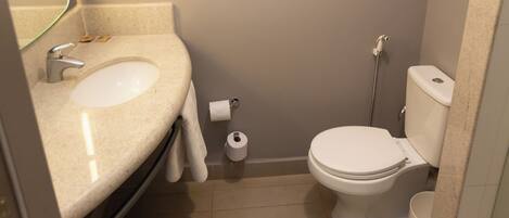 A small bathroom with a sink, toilet, and a mirror.