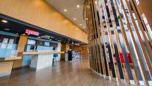 A modern hotel lobby with a reception desk, seating area, and a decorative wooden column. - ibis Parauapebas (Parauapebas)