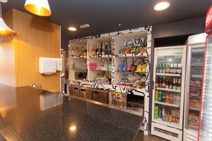 Una cocina moderna con encimeras de granito, microondas integrado y un refrigerador lleno de bebidas y aperitivos.