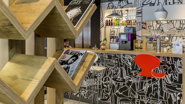 A bar area with a counter, a clock, and a wall with abstract art. - ibis Parauapebas (Parauapebas)