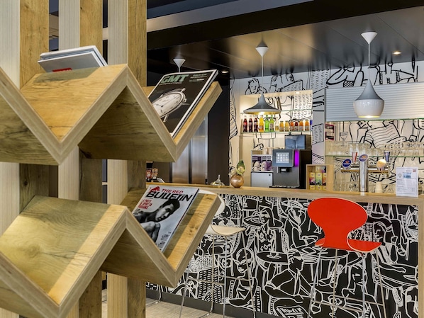 Un espace bar avec un comptoir, une horloge et un mur orné d’œuvres d’art abstraites.