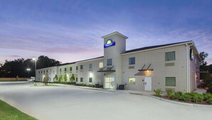 A Days Inn hotel with a central tower, multiple rooms, and a parking lot. - Days Inn by Wyndham Baton Rouge Airport (Baton Rouge)