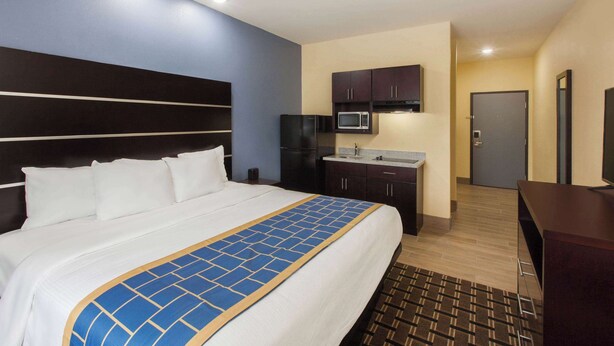 A hotel room with a large bed, a kitchenette with a microwave, and a TV. - Days Inn by Wyndham Baton Rouge Airport (Baton Rouge)