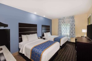 A hotel room with two beds, a desk, a TV, and a bathroom.
