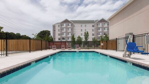 A swimming pool with a brick border, surrounded by a fence and lounge chairs. - Days Inn by Wyndham Baton Rouge Airport (Baton Rouge)