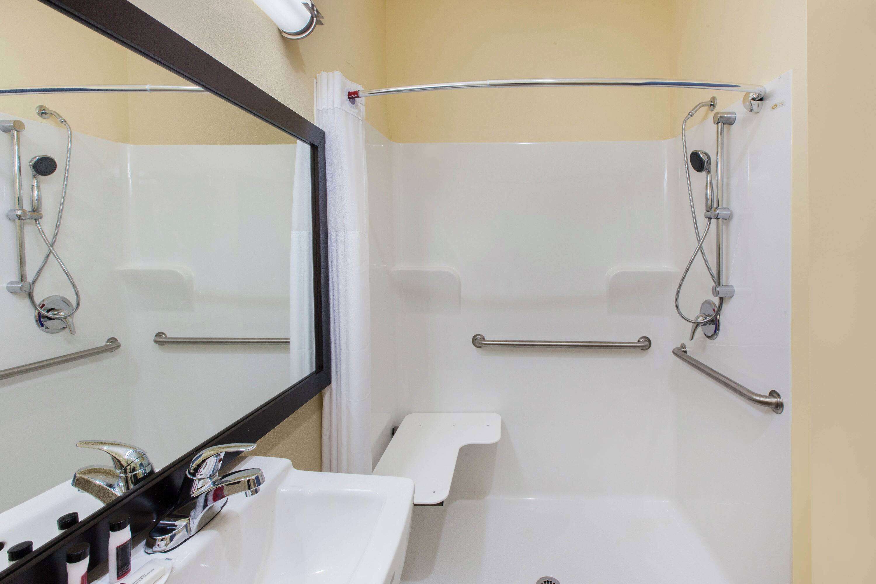 A bathroom with a white sink, mirror, and shower area.